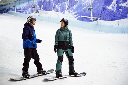 an adult on a private snowboarding lesson on the main slope with their snowboarding instructor