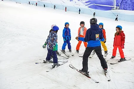 Group of children on skis being briefed by their instructor