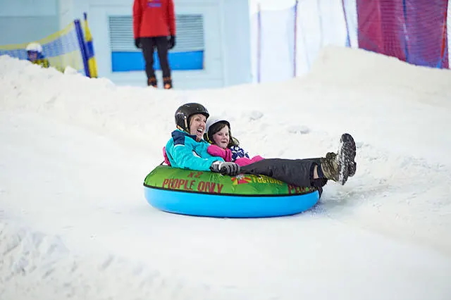 Two people in an inflatable donut on the slope at Chill Factor<sup>e</sup>