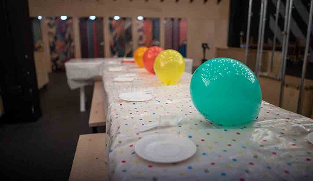 a table with a spotty table cover, baloons and paper plates set ready for a party