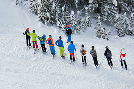 Group of skiers stood in a row with an instructor in the mountains