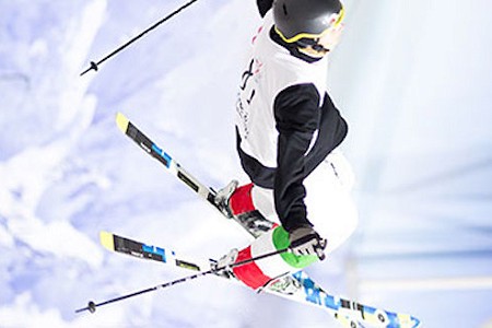 A skier performing a trick causing them to rotate upside down, they are wearing black and white