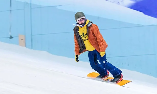 Man in bright clothing, snowboarding from left to right