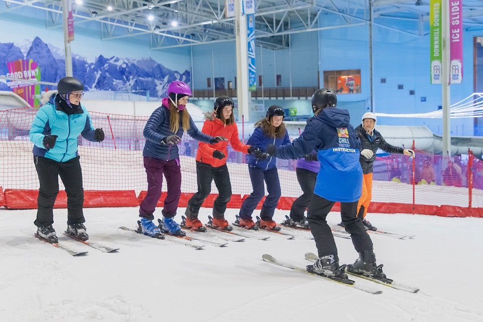 a group on people stood in a row doing on their skiing lesson on the slope
