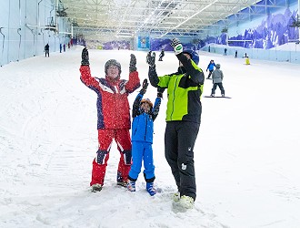 family having fun in the snow with their arms in the air and smiles on their face