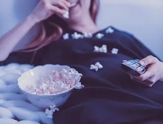Woman eating popcorn while watching TV