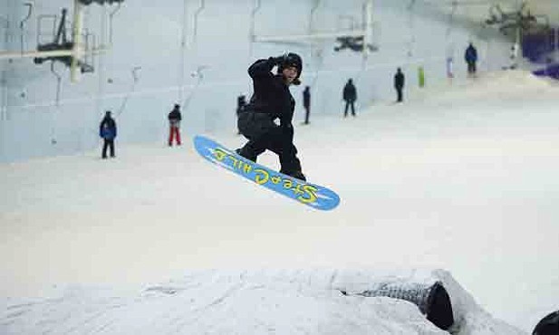 someone performing a trick on their blue and yellow snowboard in their black coat and pants
