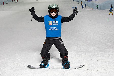 Child in snowboard gear looking to camera. Stood on snow slope at Chill Factor<sup>e</sup>