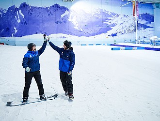 Chill Factor<sup>e</sup> snowsports instructor high fiving a snowboarder at indoor ski slope