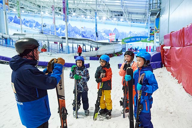 Group of children in ski gear at Chill Factor<sup>e</sup> having a briefing from an instructor