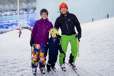 Two adults and a child in ski gear posing for a photo on the snow slope at Chill Factor<sup>e</sup>