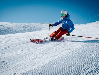 person skiing in a snowy location wearing a blue jacket and orange pants