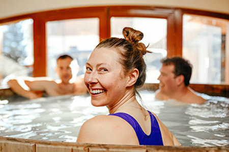 Woman sat in hot tub, turns her head to camera