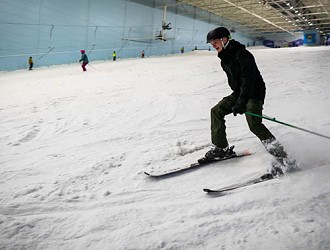Chill Factor<sup>e</sup> customer in black winter clothing parallel skiing down indoor ski slope
