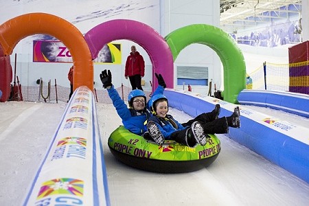 Two children in inflatable donut, sliding down the snow slope at Chill Factor<sup>e</sup>