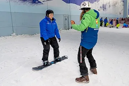 Snowboarder and instructor talking on a snow slope